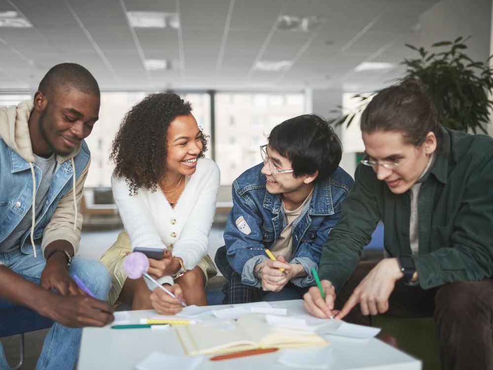 Jovens em uma reunião descontraída, representando brainstorming para desenvolver ações comerciais para captação de alunos.