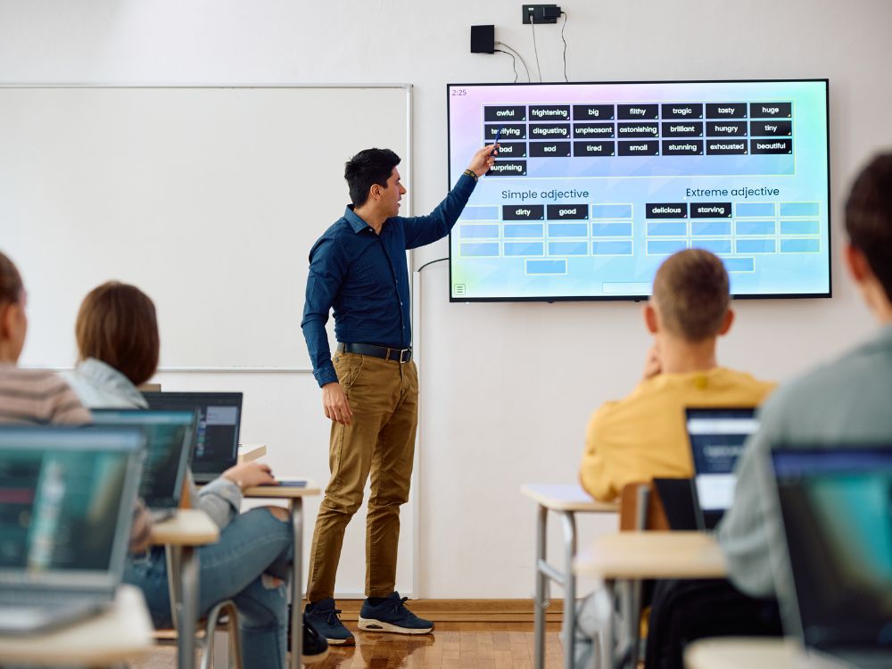 Professor utilizando recursos tecnológicos em aula ilustra perfeitamente o que é gestão de sala de aula com apoio de ferramentas digitais.
