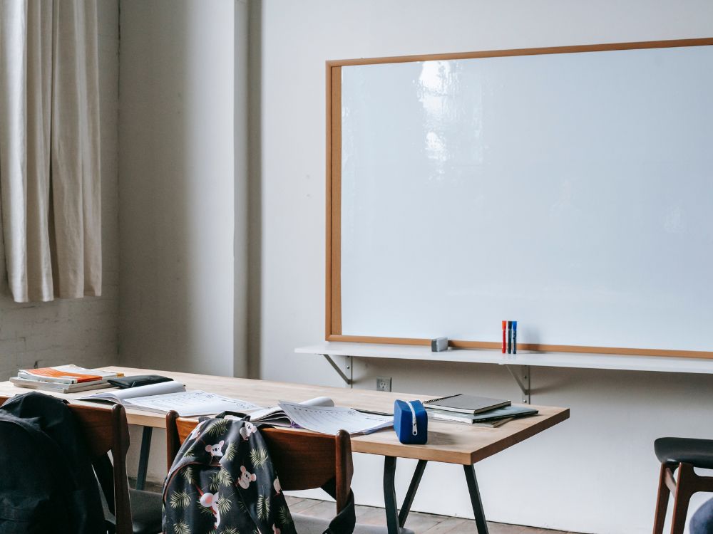 Sala de aula vazia com quadro branco e materiais organizados, essencial na gestão da aprendizagem em sala de aula.