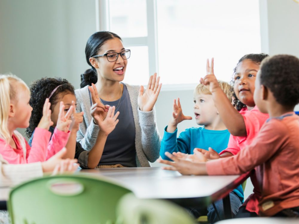 Professora interagindo com crianças em sala representa na prática o que é gestão de sala de aula com foco no desenvolvimento e organização.