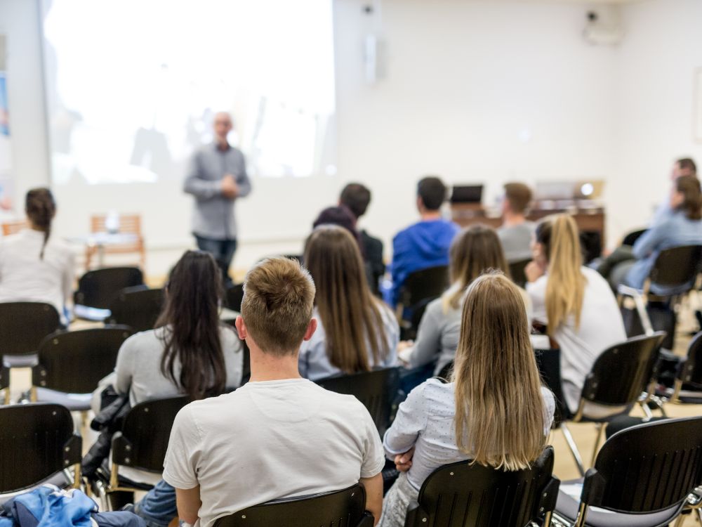 Turma reunida em sala assistindo a apresentação sobre o novo calendário do e-MEC e suas implicações para instituições de ensino superior.