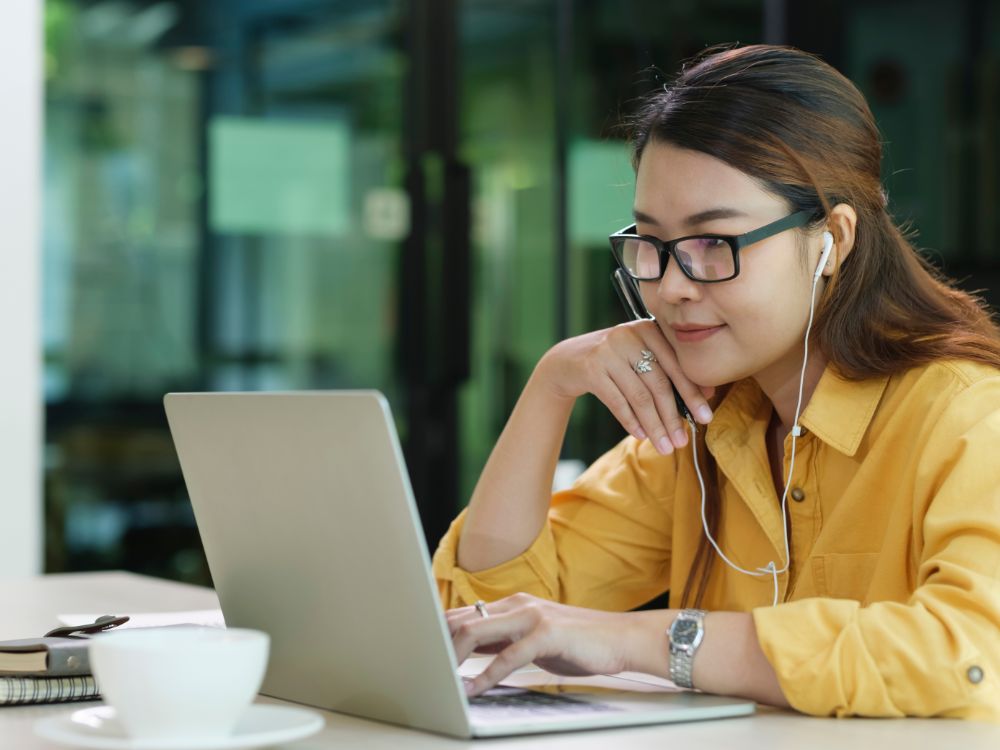 Jovem usando notebook com fones de ouvido estuda de forma remota com apoio de plataforma de gestão escolar que organiza rotinas e comunicações.