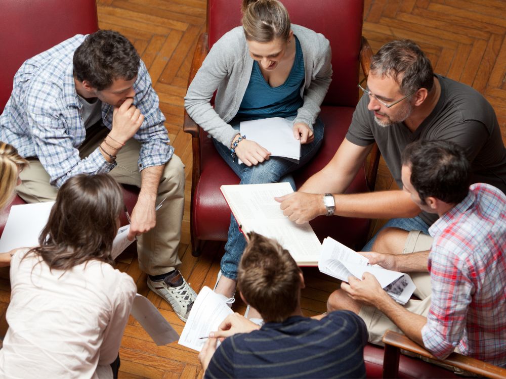 Reunião de professores debatendo processos pedagógicos sem apoio de software de gestão escolar para integrar dados e facilitar decisões.