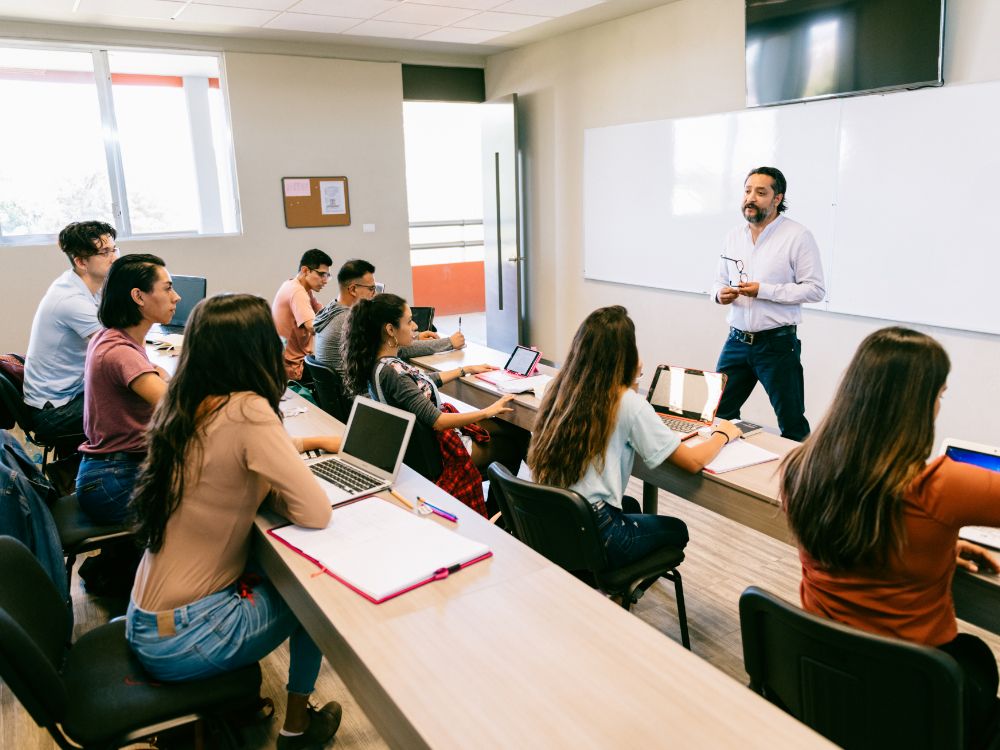 Alunos em sala de aula presencial durante explicação de professor sobre as mudanças no calendário do e-MEC e os novos prazos regulatórios.