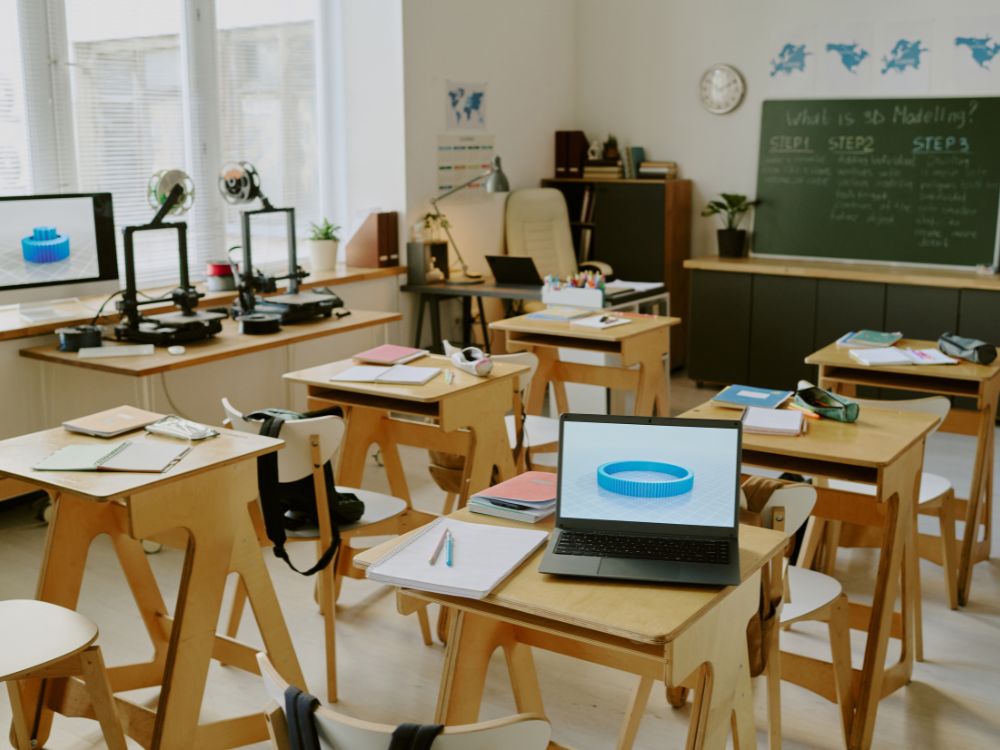 Ambiente escolar moderno com ferramentas educacionais como impressoras 3D e notebooks, promovendo aprendizado prático e tecnológico.