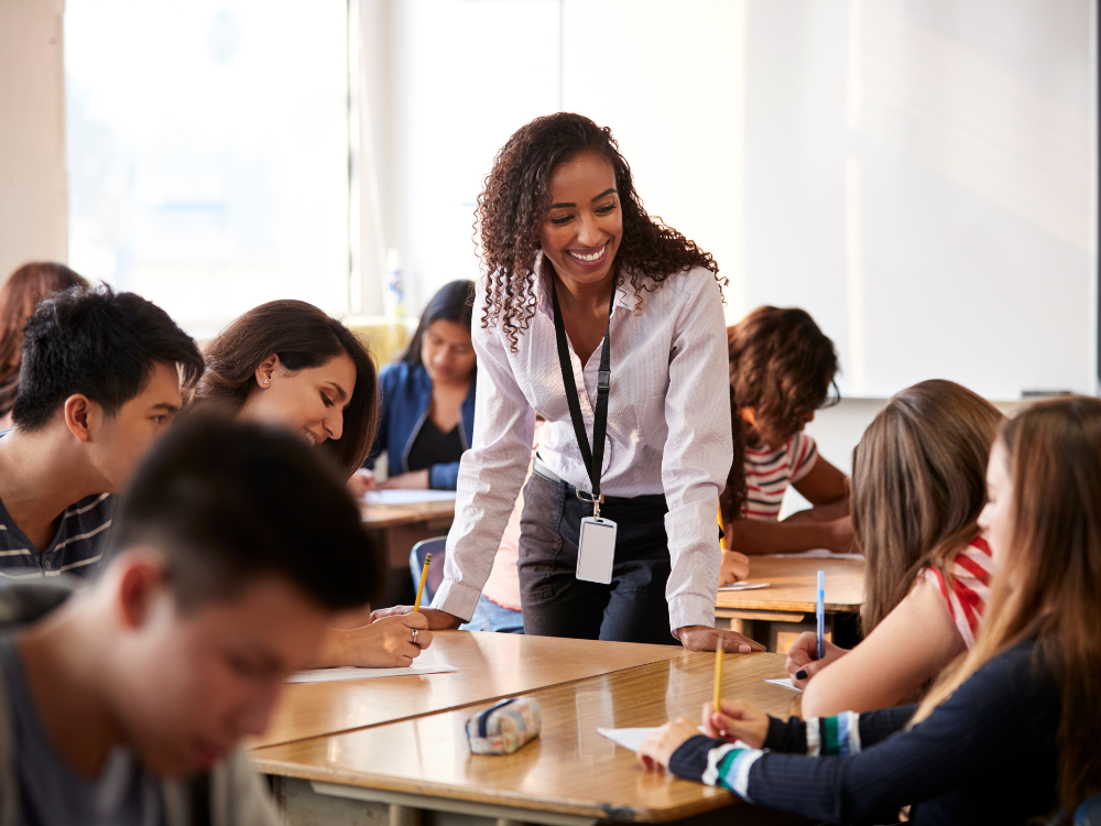 Professora interage com estudantes durante atividade escolar, destacando a importância da gestão de alunos no acompanhamento pedagógico.