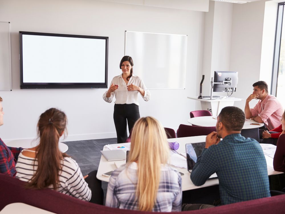 Professora conduz apresentação sobre ferramentas digitais para aprimorar a gestão de alunos em instituições de ensino superior.
