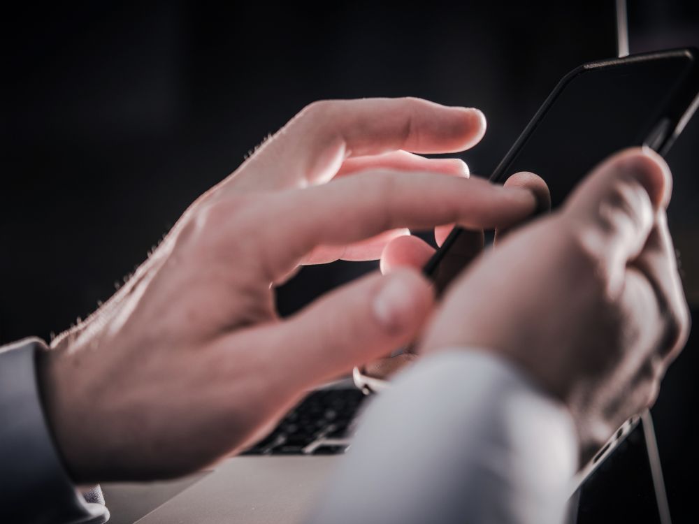 Mãos de responsável acessando a Agenda Digital Escolar, reforçando a comunicação em tempo real entre escola e famílias.