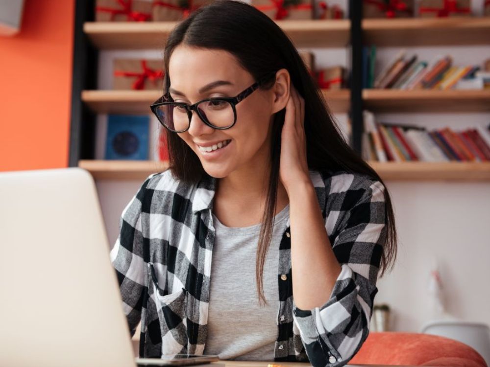 Estudante sorrindo ao estudar online em notebook, mostrando na prática o que é educação digital e como ele amplia autonomia e flexibilidade no aprendizado.