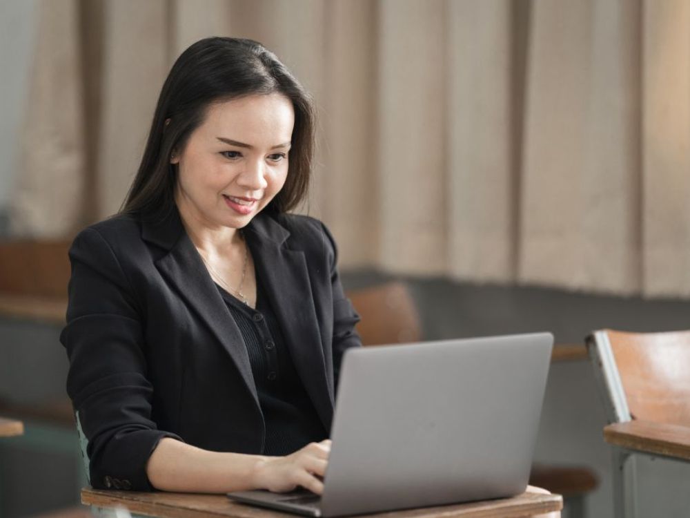 Professora utilizando notebook em sala de aula, destacando o que é educação digital e como plataformas digitais otimizam gestão e aprendizado escolar.