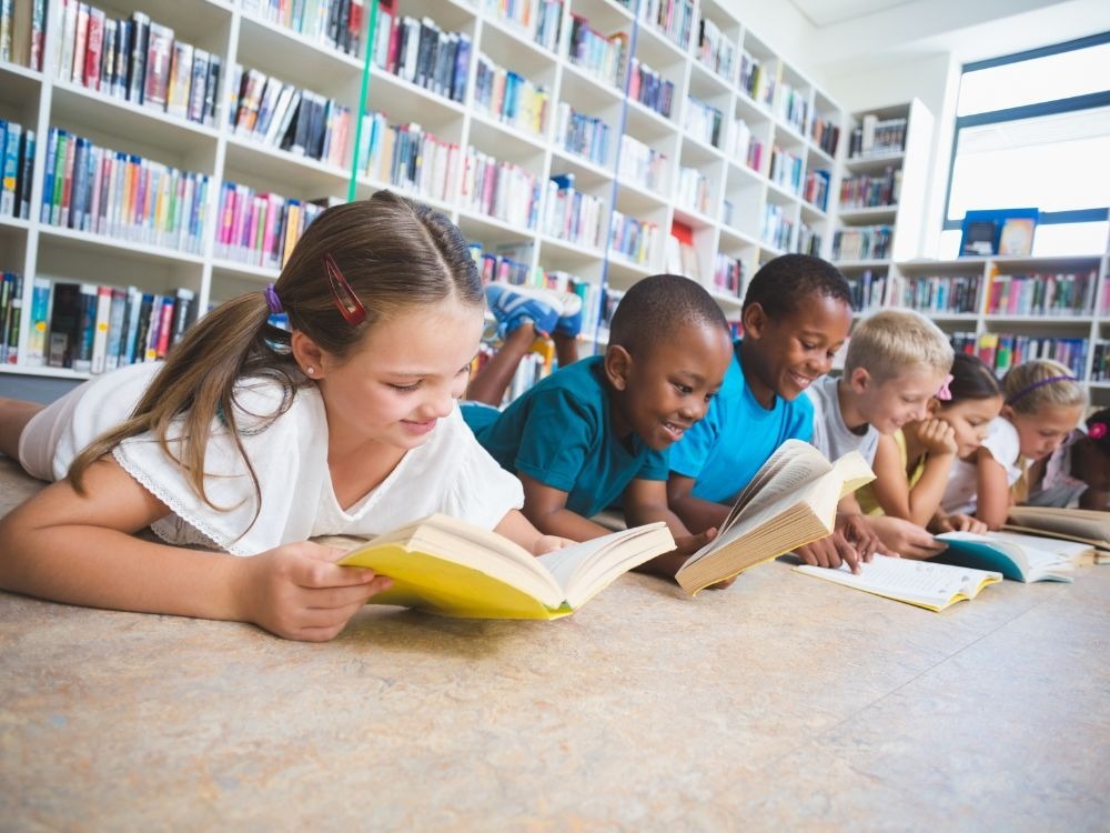 Leitores infantis aproveitam espaço de leitura, exemplo inspirador de como organizar biblioteca escolar para incentivar a leitura.