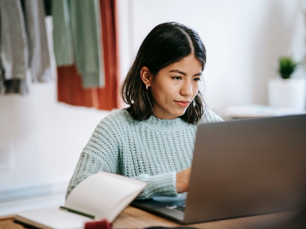 Jovem estudando online com laptop e caderno em casa – conceito de educação à distância, ensino digital e aprendizado remoto com tecnologia.