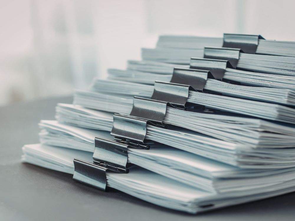 Pilha de documentos organizados, simbolizando o desafio que explica o que é GED e a importância da digitalização de arquivos.