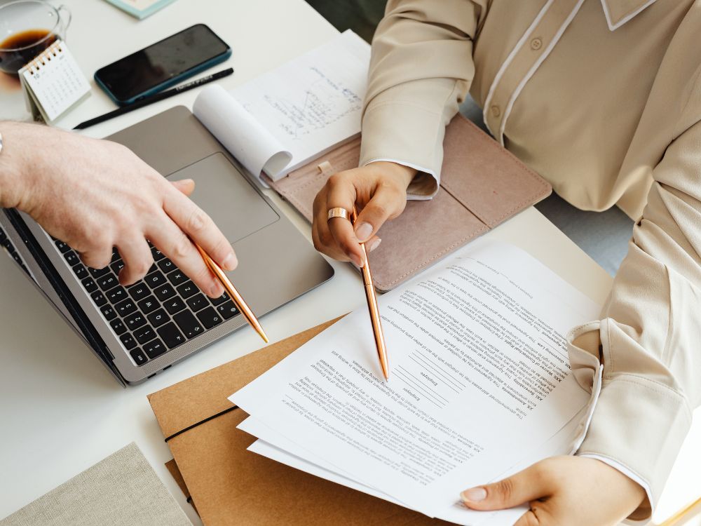 Profissionais analisando documentos físicos e digitais, exemplificando o que é GED na gestão e controle de documentos institucionais.