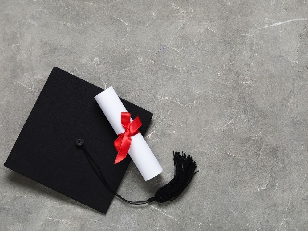 Capelo de formatura e diploma simbolizando fatores relacionados à evasão no ensino superior e conclusão de cursos acadêmicos