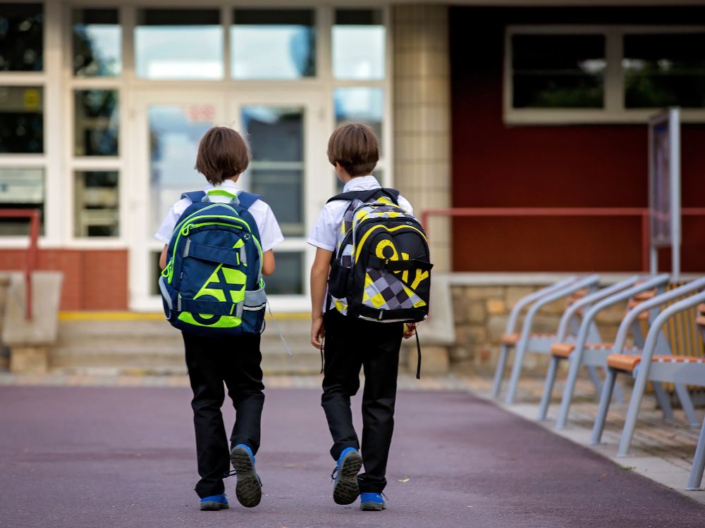 Crianças indo para a escola com mochilas, imagem que representa acesso à educação e fatores iniciais nos indicadores de evasão escolar.