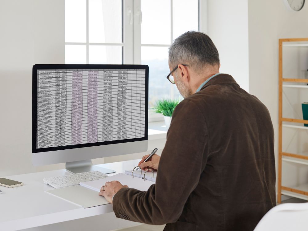 Profissional analisando planilhas no computador, situação que representa controle financeiro e acompanhamento da inadimplência na escola particular.