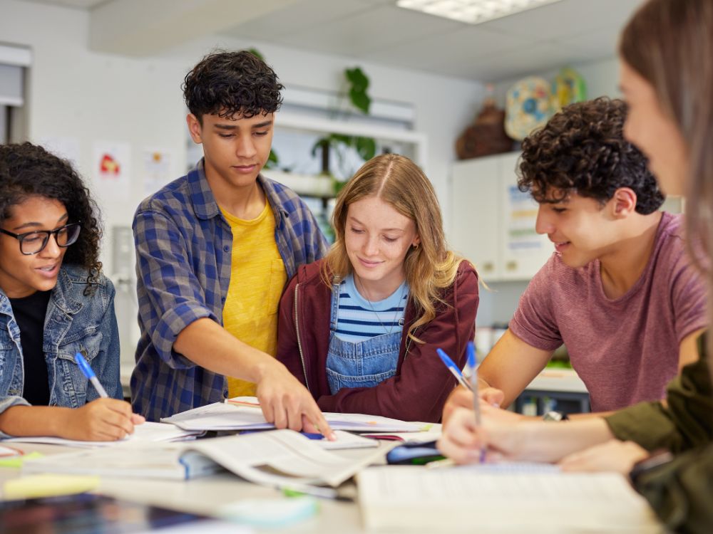 Comunicação na escola entre alunos em sala de aula durante atividade em grupo, incentivando interação, aprendizado colaborativo e troca de ideias.